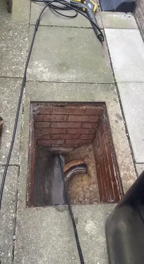 A blocked drain being jetted through the manhole
