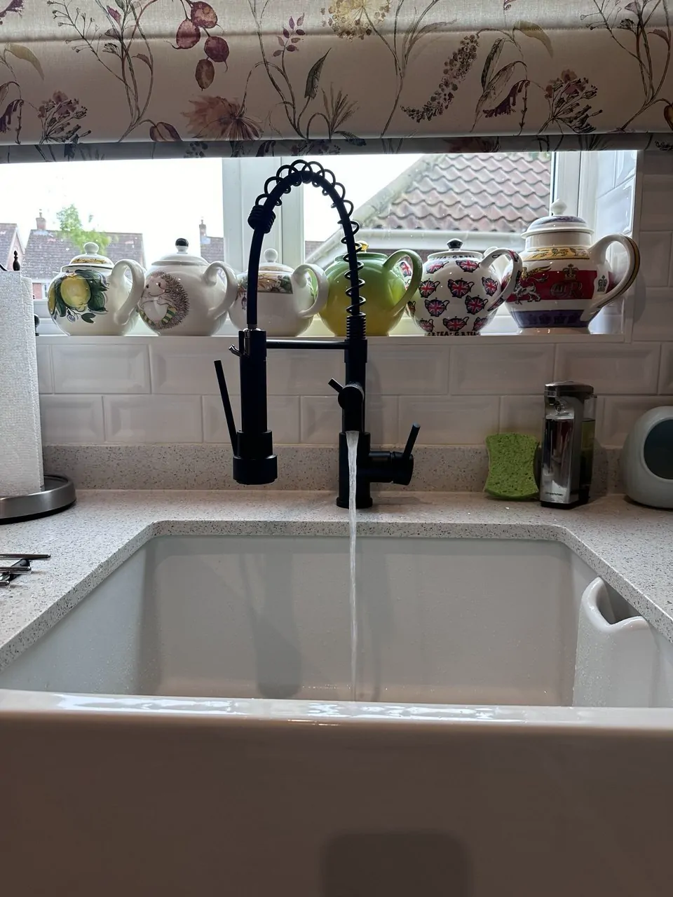 A black kitchen mixer tap running into a white ceramic sink