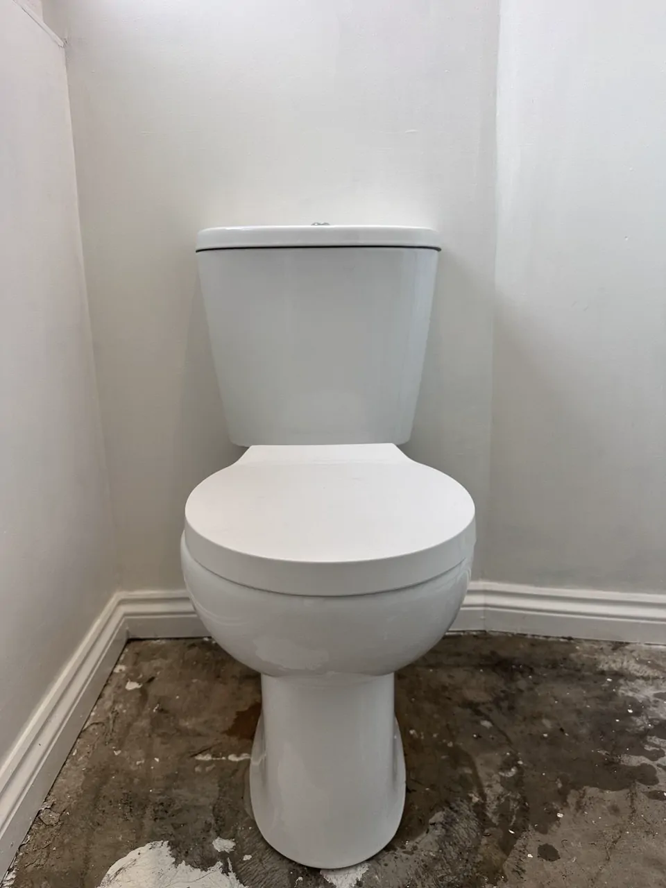 A new white close-coupled toilet fitted in a small cloakroom