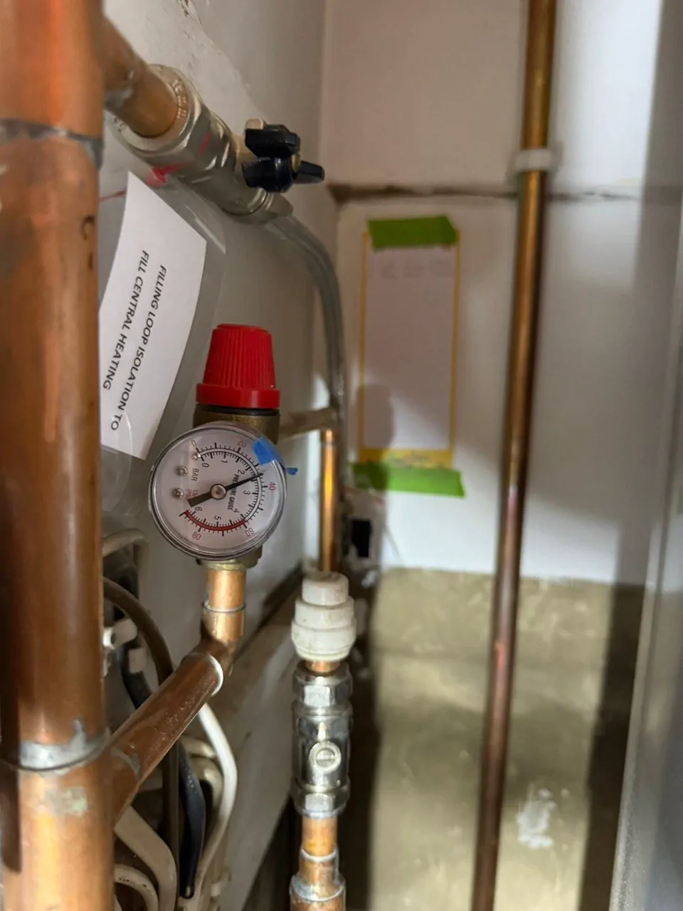 A pressure gauge and a red-capped relief valve on copper pipework