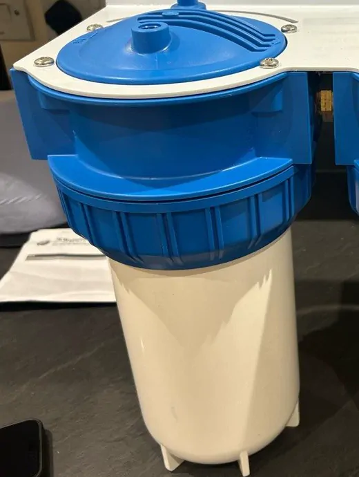A blue and white water filter housing on a kitchen worktop before fitting