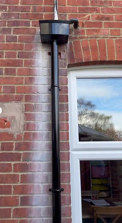 A new gutter downpipe fitted to a brick wall